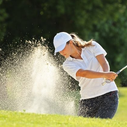 golfista haciendo una sacada de bunker usando polo de golf de mujer